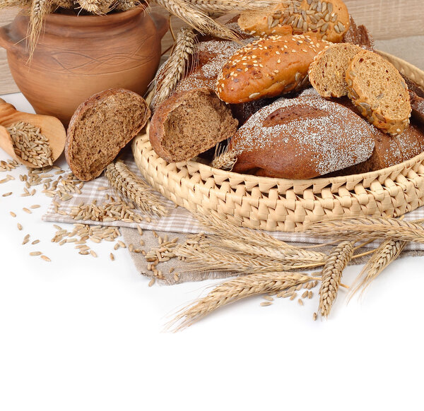 Fresh bread in a wattled basket, ears and grain on a white background with a place for the text.