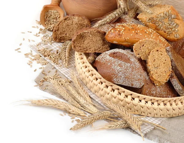 Pan fresco en una cesta de mimbre, espigas y grano sobre un fondo blanco con un lugar para el texto . —  Fotos de Stock