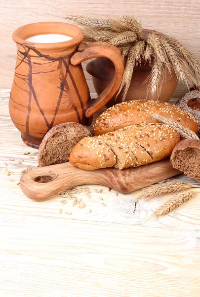 Färskt bröd, öron, säd och kannan på en trä bakgrund med en plats för text. — Stockfoto