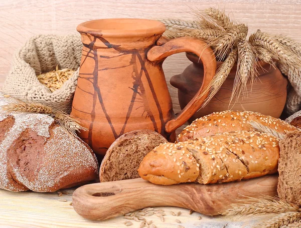 Pâine proaspătă, urechi, cereale și ulcior pe un fundal din lemn deschis, cu un loc pentru text . — Fotografie, imagine de stoc