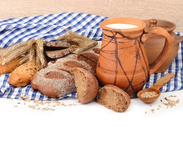 Färskt bröd, öron och korn på en blå rutig servett på en vit bakgrund med en plats för text. — Stockfoto