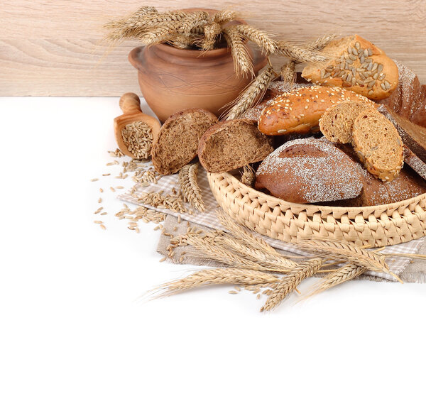 Fresh bread in a wattled basket, ears and grain on a white background with a place for the text.