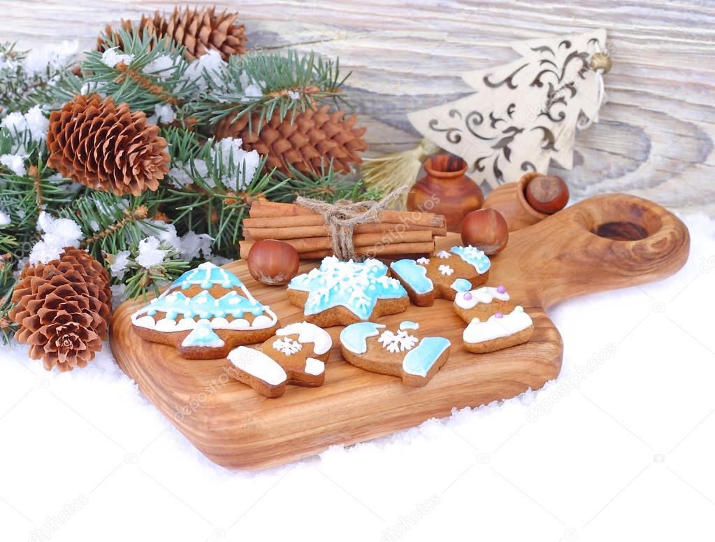 Christmas ginger cookies in blue glaze, nuts and cones on snow on a white background. A Christmas background with a place for the text.