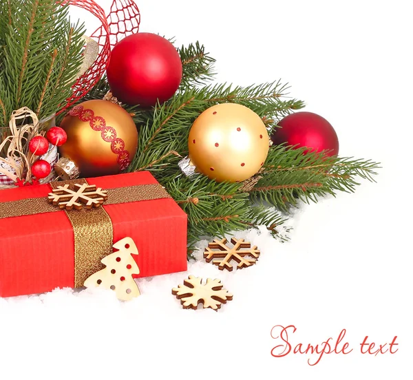 Altın ve kırmızı Noel topları ve bir hediye kutusu beyaz zemin üzerinde bir Noel ağacının dalları karla kaplı üzerinde Noel kompozisyonu. Bir Noel arka plan metni için bir yer ile.