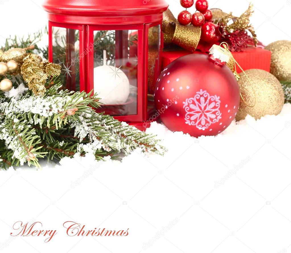 Christmas composition with a red small lamp candlestick and golden and red Christmas balls on snow-covered branches of a Christmas tree on a white background. A Christmas background with a place for the text.