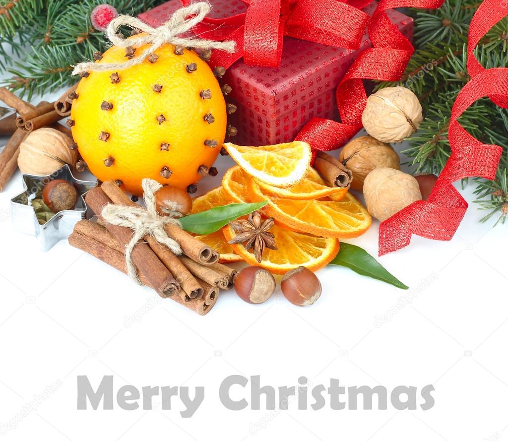 Dried oranges, cinnamon and nuts on branches of a Christmas tree on a white background. A Christmas background with a place for the text.