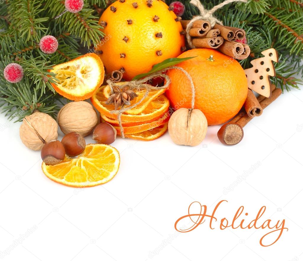 Dried oranges, cinnamon and nuts on branches of a Christmas tree on a white background. A Christmas background with a place for the text.
