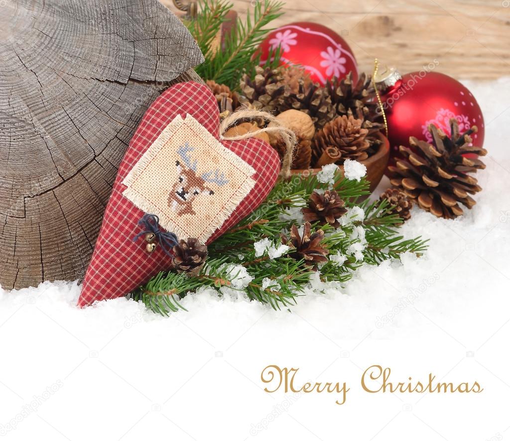 Textile checkered heart with a deer and Christmas balls on snow on a wooden background. A Christmas background with a place for the text.