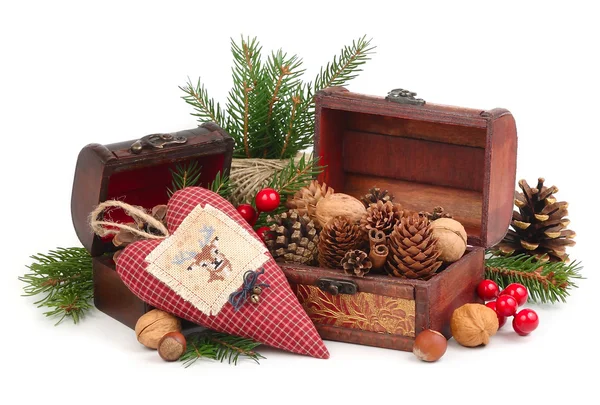 El corazón textil a cuadros con el ciervo bordado, los conos y las nueces sobre las ramas del árbol de Navidad sobre la nieve sobre el fondo blanco . — Foto de Stock