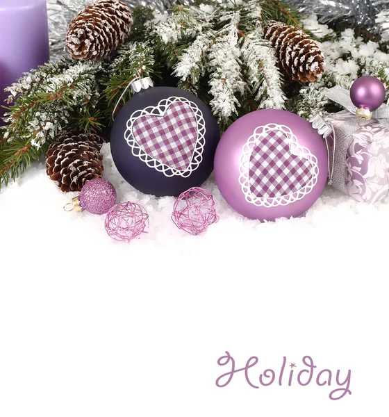 Violet Christmas balls with heart and snow-covered branches of a Christmas tree with cones on a white background. A Christmas background with a place for the text. — Stok fotoğraf