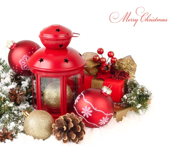 Red lamp candlestick and red and golden Christmas balls on snow-covered branches of a Christmas tree on snow on a white background. A Christmas background with a place for the text. — Stock fotografie