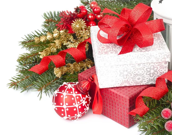 Cajas de regalo de Navidad con lazo rojo y bola roja de Navidad sobre ramas de árbol de Navidad sobre fondo blanco. Un fondo navideño con un lugar para el texto . — Foto de Stock