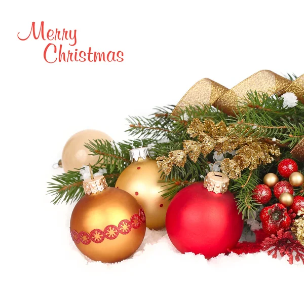 Red and golden Christmas balls on branches of a Christmas tree on snow on a white background. A Christmas background with a place for the text. 图库图片