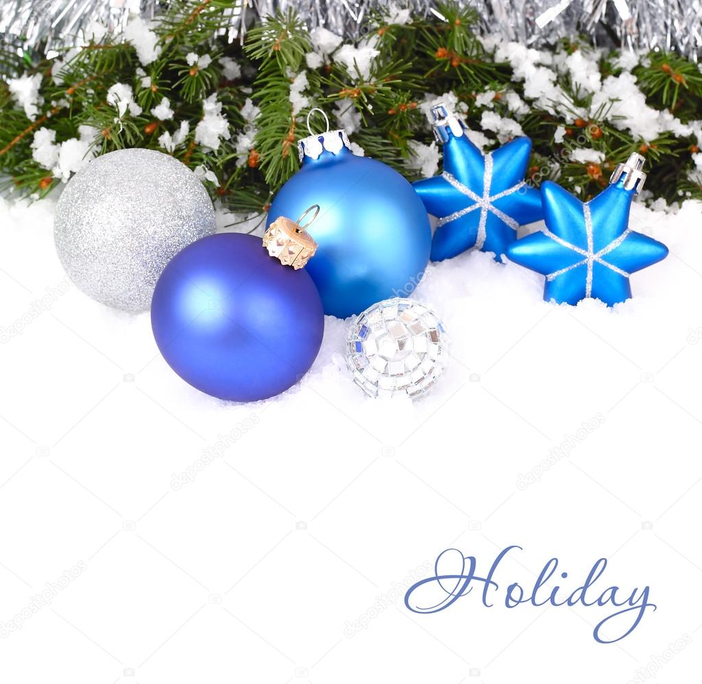 Blue and silvery Christmas balls and stars and branches of a Christmas tree on snow on a white background. A Christmas background with a place for the text.
