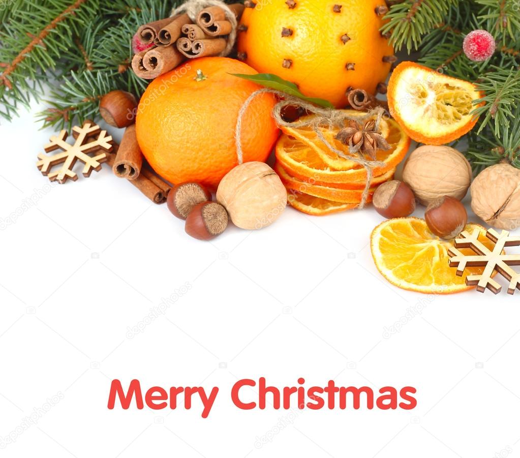 Dried oranges, nuts and cinnamon on branches of a Christmas tree on a white background. A Christmas background with a place for the text.