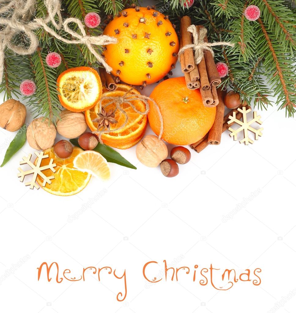 Dried oranges, nuts and cinnamon on branches of a Christmas tree on a white background. A Christmas background with a place for the text.