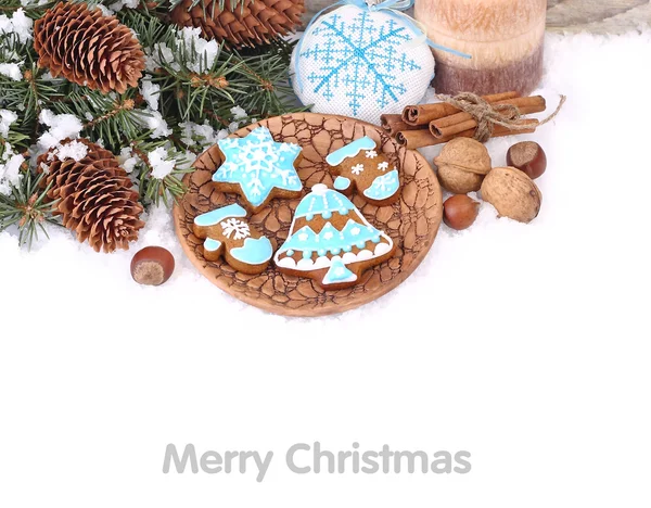 Biscoitos de gengibre de Natal e nozes perto de ramos de uma árvore de Natal e cones em um contexto branco. Um fundo de Natal com um lugar para o texto . — Fotografia de Stock