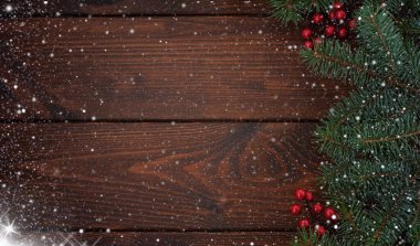 Ahşap zemin üzerinde kırmızı böğürtlen olan çam dalları. Noel karlı arka planı. Mutlu yıllar! Metnin için boşluk kopyala.