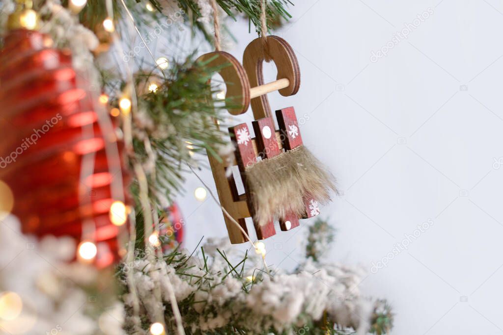 Wooden sled, Christmas toys, garlands hang on the Christmas tree. Christmas background. Happy New Year!Copy space for text.