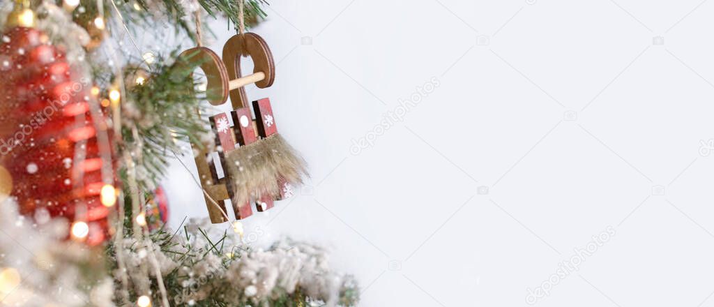 Wooden sled, Christmas toys, garlands hang on the Christmas tree. Christmas background. Happy New Year!Copy space for text. Banner