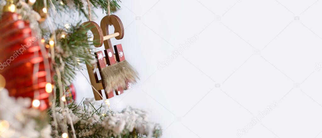 Wooden sled, Christmas toys, garlands hang on the Christmas tree. Christmas background. Happy New Year!Copy space for text. Banner