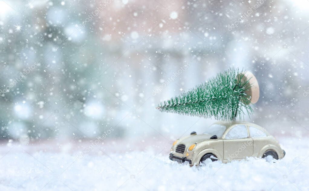 Retro toy car carrying tiny Christmas tree In Snowy Landscape. Fairytale, miniature scenery with snow and forest. Christmas cards. Trucking.