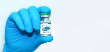 Harkiv. Ukrayna. 23 Kasım 2020. Lateks eldiven giyen bir doktorun ya da yerlinin elinde mavi arka planda Pfizer ve Biyoteknik ile işbirliği içinde geliştirilen Coronavirus aşısı bulunuyor..