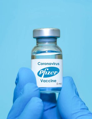 Harkiv. Ukrayna. 23 Kasım 2020. Lateks eldiven giyen bir doktorun ya da yerlinin elinde mavi arka planda Pfizer ve Biyoteknik ile işbirliği içinde geliştirilen Coronavirus aşısı bulunuyor..