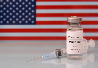 Amerikan bayraklarında şırınga olan bir şişedeki aşı. Tıp, sağlık ve bilim konsepti. Coronavirus aşısı.
