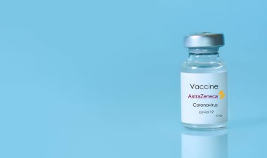 Harkiv. Ukrayna. 9 Ocak 2021. AstraZeneca logosuyla Coronavirus aşısı şişesi mavi bir arka plan. Tıp, sağlık ve bilim konsepti. Metin için alan kopyala.