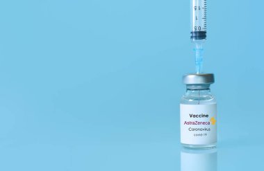 Harkiv. Ukrayna. 9 Ocak 2021. Şırınga, Coronavirus aşı şişesi AstraZeneca logosu mavi bir arka plan. Tıp, sağlık ve bilim konsepti. Uzayı metin için kopyala. Pankart