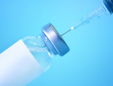 Mavi zemin üzerinde şırınga olan bir şişedeki aşı. Tıp, sağlık ve bilim konsepti. Coronavirus aşısı.