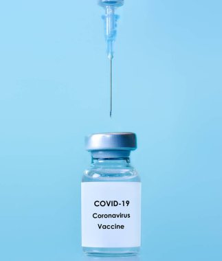 Mavi zemin üzerinde şırınga olan bir şişedeki aşı. Tıp, sağlık ve bilim konsepti. Coronavirus aşısı.