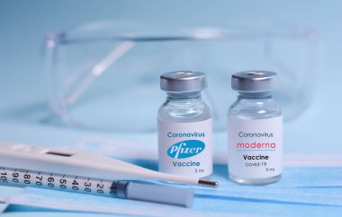 Harkiv. Ukrayna. 1 Şubat 2021. İçinde Moderna logosu, Pfizer logosu, şırınga, maske, termometre ve koruyucu gözlük olan Coronavirus aşı şişeleri. Tıp konsepti, sağlık hizmetleri