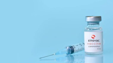 Harkiv. Ukrayna. 9 Ocak 2021. Şırınga, Coronavirus aşısı şişesi. Sinovac logosu mavi bir zemin. Tıp, sağlık ve bilim konsepti. Pankart