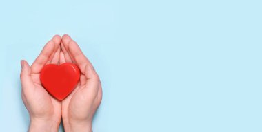 Kırmızı kalp mavi arka planda izole edilmiş bir adamın ellerinde. Sağlık ve hastane tıbbi konsepti. Sevgililer Günü 'nün sembolü. Metin için yeri olan üst görünüm. Pankart