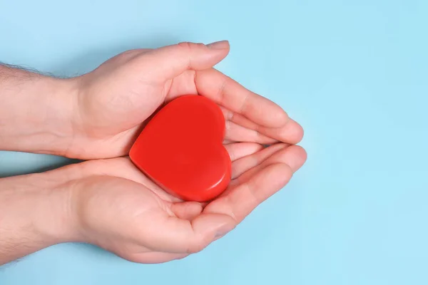 Red heart in man\'s hands isolated on blue background. Healthcare and hospital medical concept. Symbolic of Valentine day.Top view with space for text.