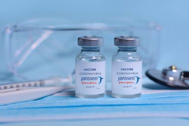 Harkiv. Ukrayna. 1 Şubat 2021. Coronavirus aşısı şişelerinde Janssen Johnson ve Johnson logosu, şırınga, maske, termometre ve koruyucu gözlük var. Tıp, sağlık ve bilim kavramı.