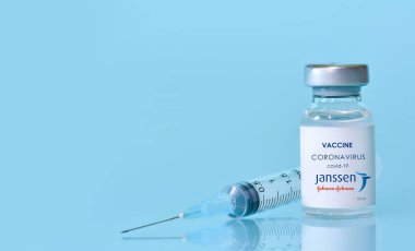 Harkiv. Ukrayna. 9 Ocak 2021. Şırınga, Coronavirus aşı şişesi. Janssen Johnson ve Johnson 'ın logosu mavi bir arka plan. Tıp, sağlık ve bilim konsepti..