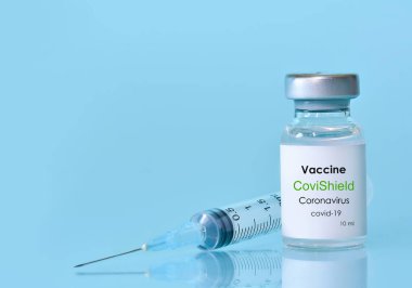 Harkiv. Ukrayna. 9 Ocak 2021. Şırınga, Coronavirus aşısı şişesi CoviShield logosu mavi bir arka plan. Tıp, sağlık ve bilim konsepti. Metin için alan kopyala.