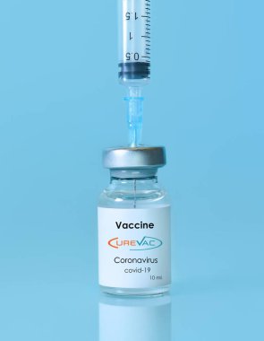 Harkiv. Ukrayna. 9 Ocak 2021. Şırınga, Coronavirus aşısı şişesi. Üzerinde Curevac logosu olan mavi bir arka plan. Tıp, sağlık ve bilim konsepti..