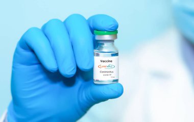 Harkiv. Ukrayna. 24 Aralık 2020. Curevac logosuyla Covid-19 aşısı. Eldivenli bir doktorun elinde mavi arka plan aşısı olan bir şişe var. Metin için boşluk kopyala.