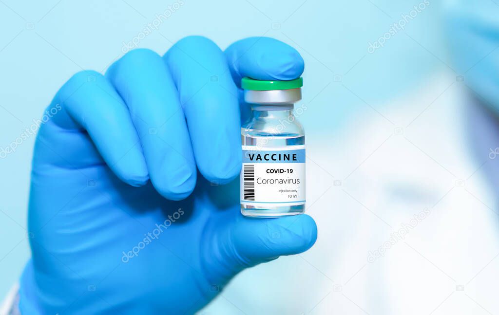 A doctor in blue gloves holding a bottle with coronavirus vaccine.The concept of medicine, healthcare and science