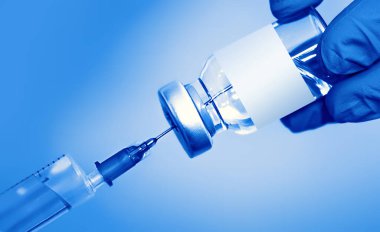 Mavi zemin üzerinde şırınga olan bir şişedeki aşı. Tıp, sağlık ve bilim konsepti. Coronavirus aşısı.