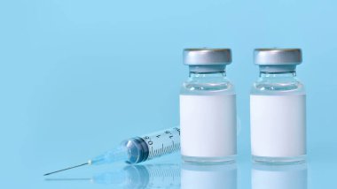 Aşılı iki şişe, mavi zemin üzerinde bir şırınga. Tıp, sağlık ve bilim konsepti. Coronavirus aşısı. Metin için yer kopyala..