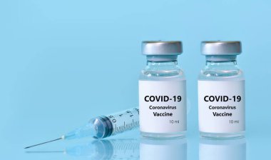 Aşılı iki şişe, mavi zemin üzerinde bir şırınga. Tıp, sağlık ve bilim konsepti. Coronavirus aşısı. Metin için yer kopyala...