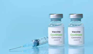 Harkiv. Ukrayna. 9 Ocak 2021. Şırınga, Coronavirus aşısı şişesi CoviShield logosu mavi bir arka plan. Tıp, sağlık ve bilim konsepti. Ders için alanı kopyala. Banner