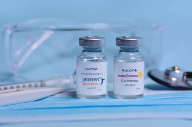 Harkiv. Ukrayna. 1 Şubat 2021. Coronavirus aşı şişeleri Janssen Johnson ve Johnson logosu ve AstraZeneca logosu, şırınga, maske, termometre, stetoskop ve koruyucu gözlüklerle.