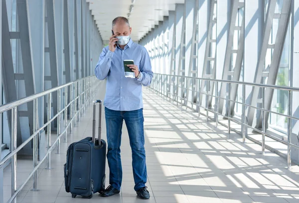 一名戴着医疗面罩的商人 带着护照 手提箱 在禽流感爆发期间在机场或购物中心打电话 洛丹奴 取消航班 — 图库照片
