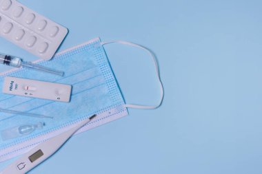 Hepatit B Virüs Testi (HBsAg) için hızlı test kaseti, tıbbi maske, şırınga, termometre, mavi zeminde ilaç. Test negatif sonuç verdi. Boşluğu kopyala